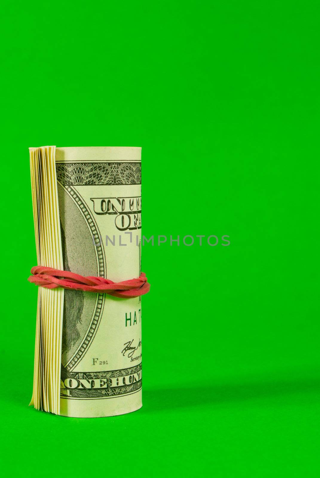 Roll of US dollars tied up with rubber over white background