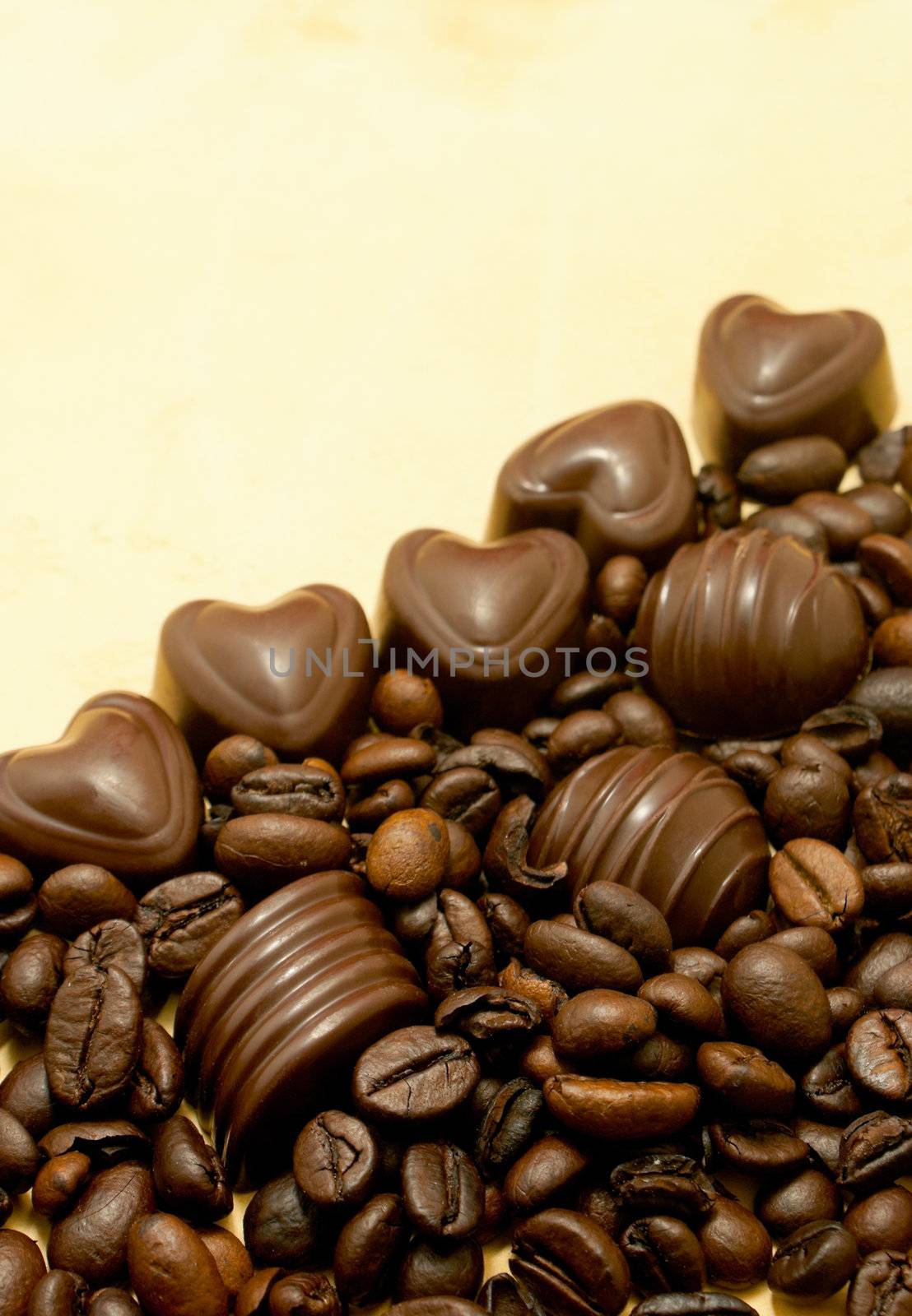 Heart shaped chocolate candies and coffee beans on grungy paper