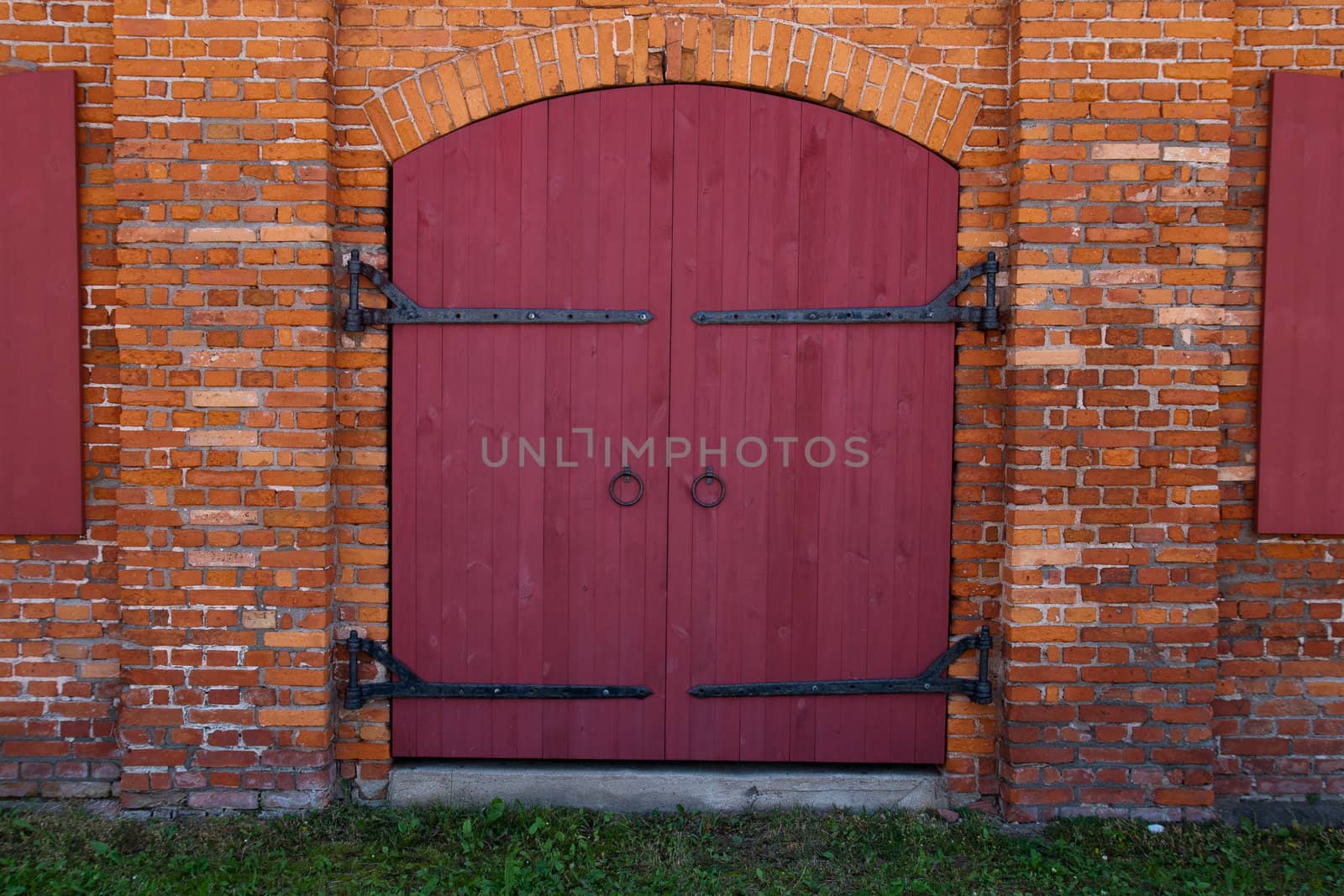 Old Red wooden door in red brick wall 