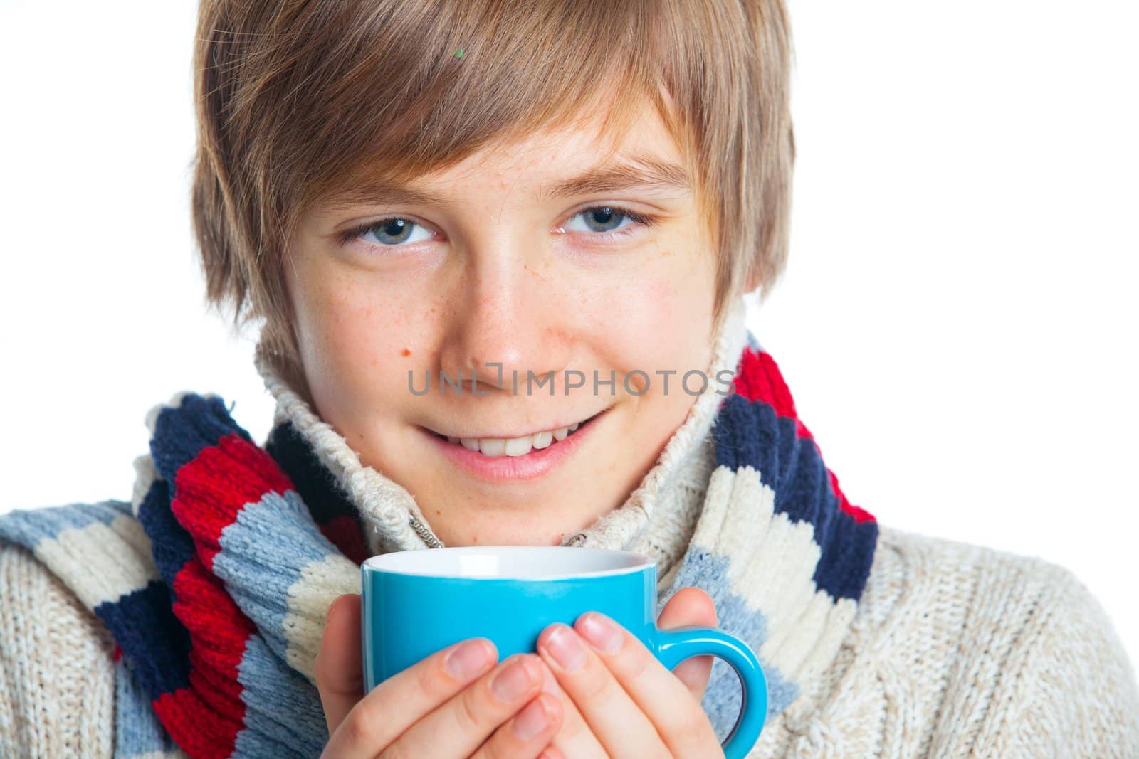 Portrait of young smiling cute frozen teenager in a scarf and with blue cup, isolated on white,