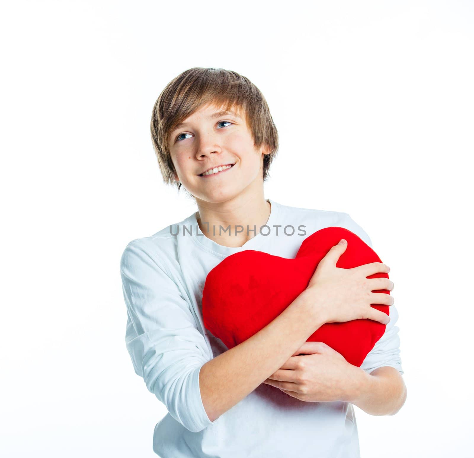 A cute young boy in love with a red plush heart in his hands. Focus on the heart.