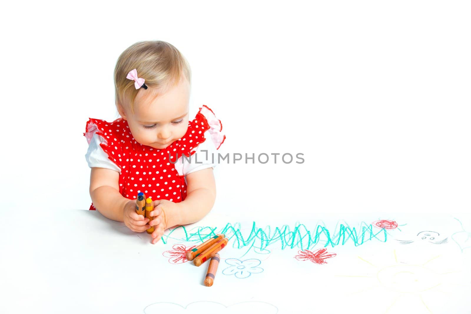 A little sweet girl draws with crayons in red, isolated on white