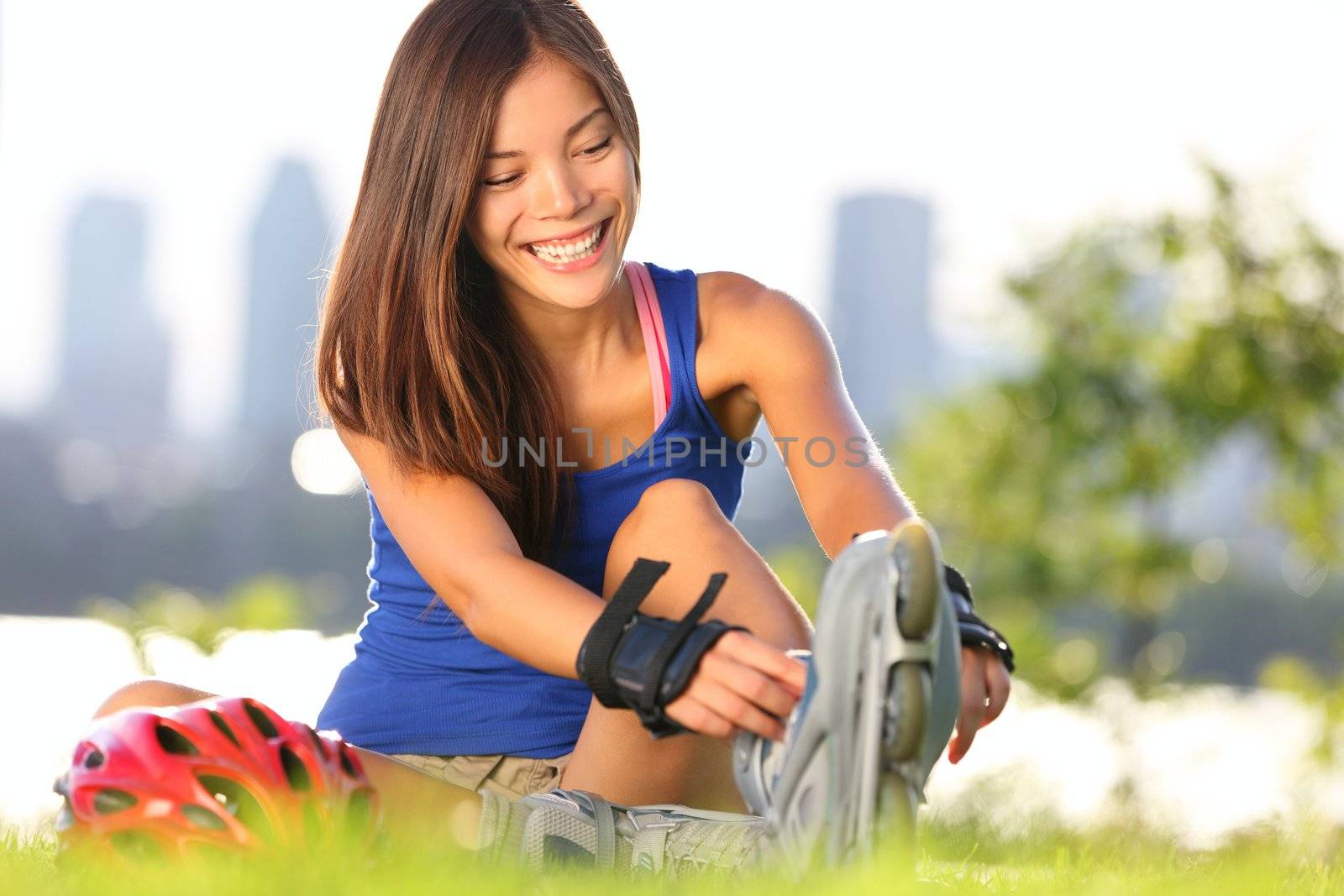 Roller skating woman putting on inline skates for rollerblading. Healthy outdoor workout woman skating outside with montreal city skyline in background.