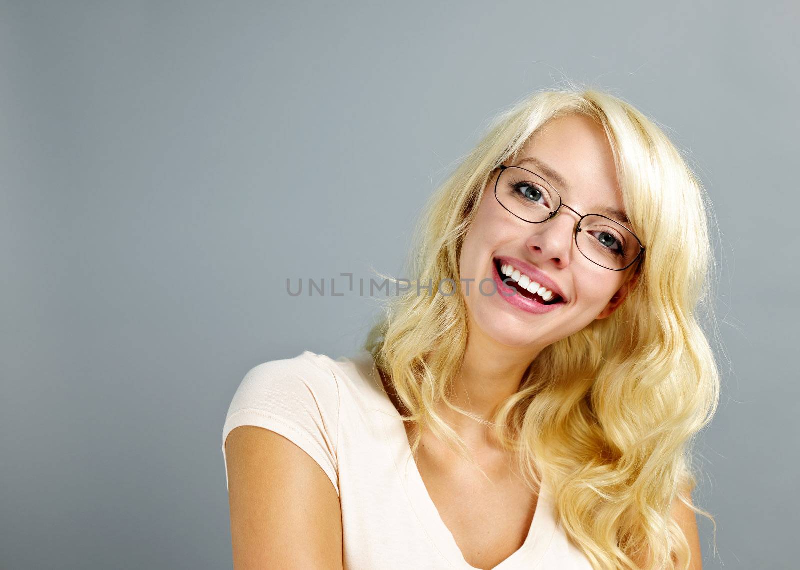 Happy young woman wearing eyeglasses on grey background