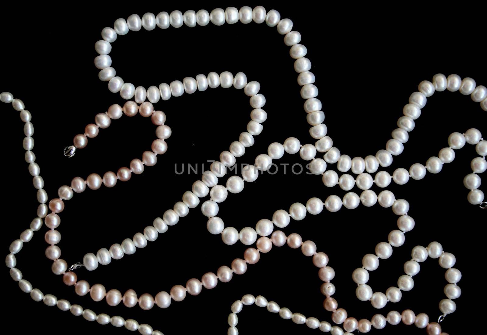 White pearls on the black silk as background 