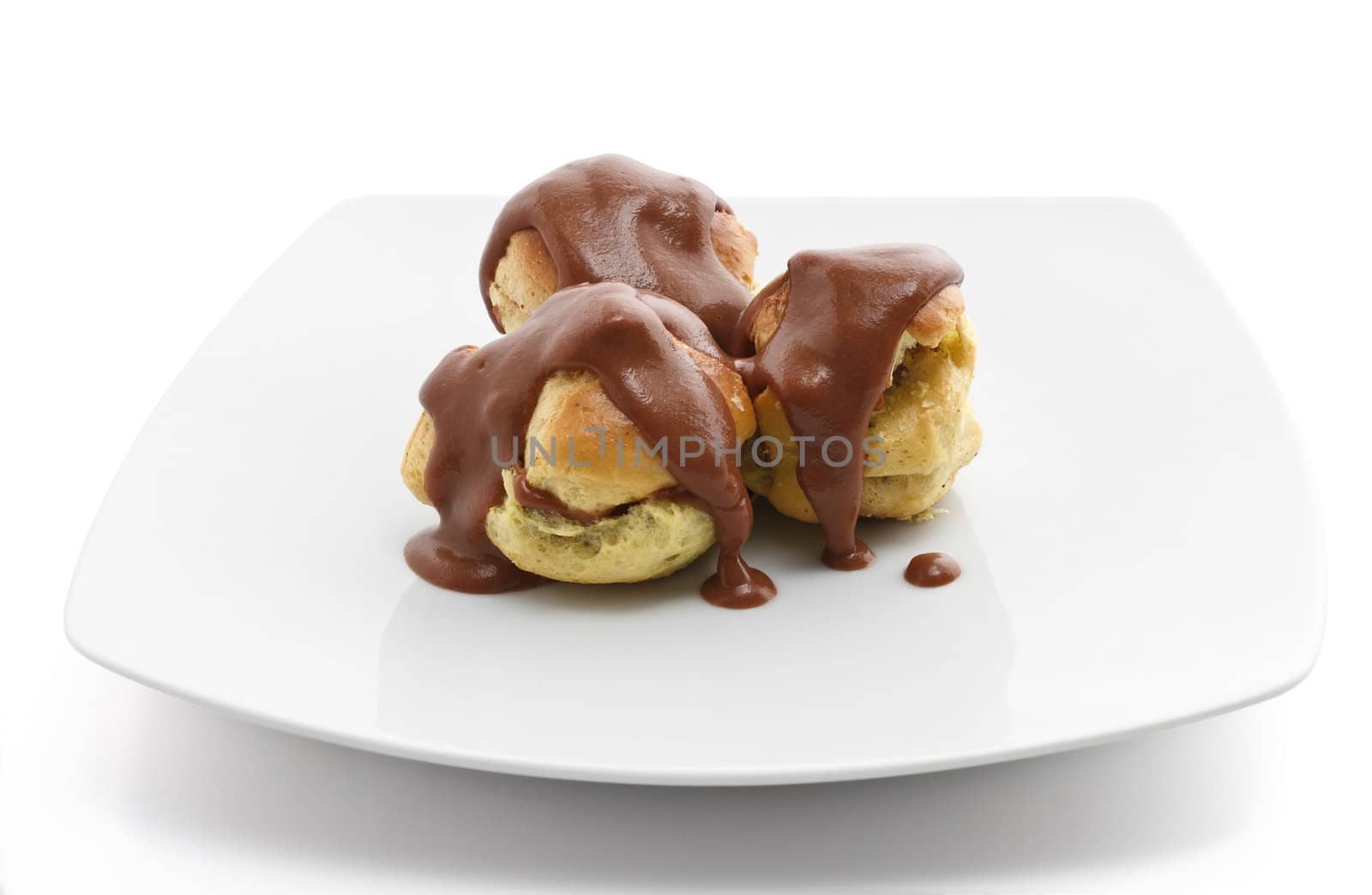 plate with three profiteroles, classic dessert with chocolate sauce 
