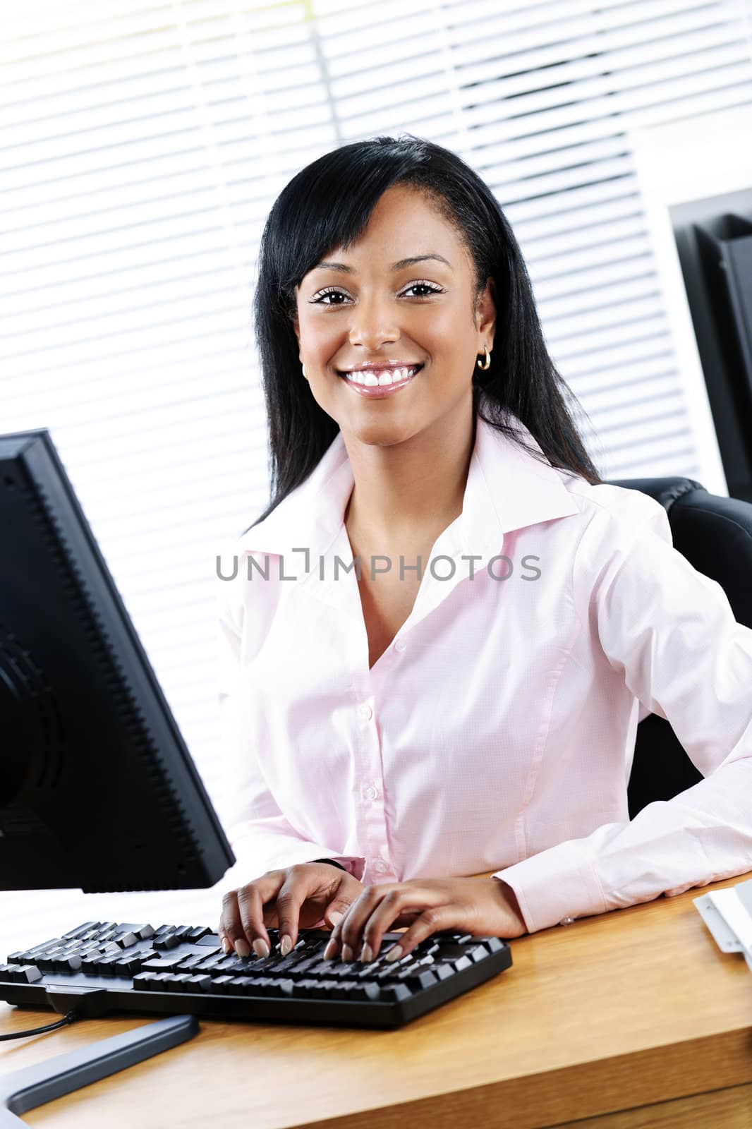 Happy black businesswoman at desk by elenathewise