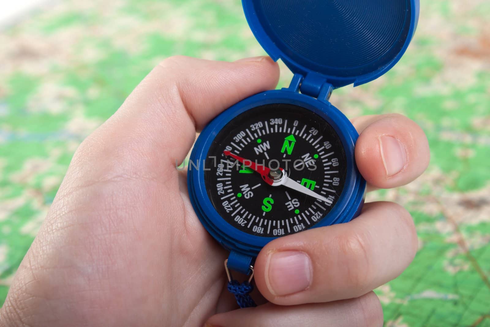 Hand holding travel north direction compass on map