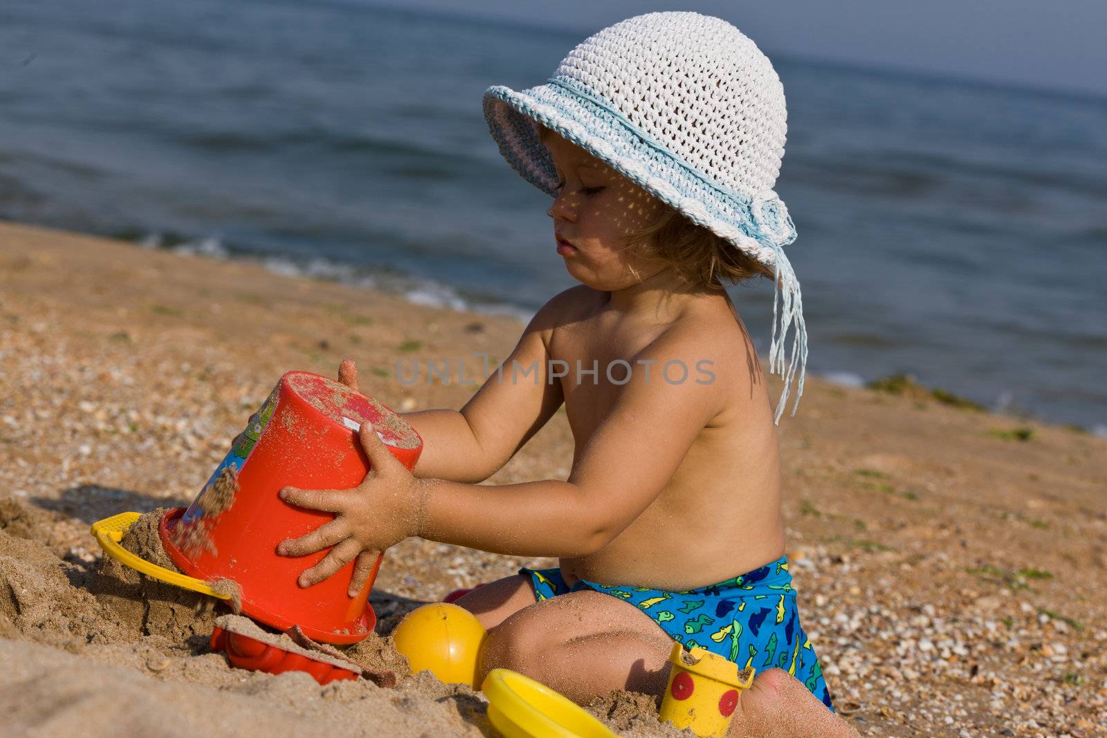 little girl in the bonnet plaing with sand