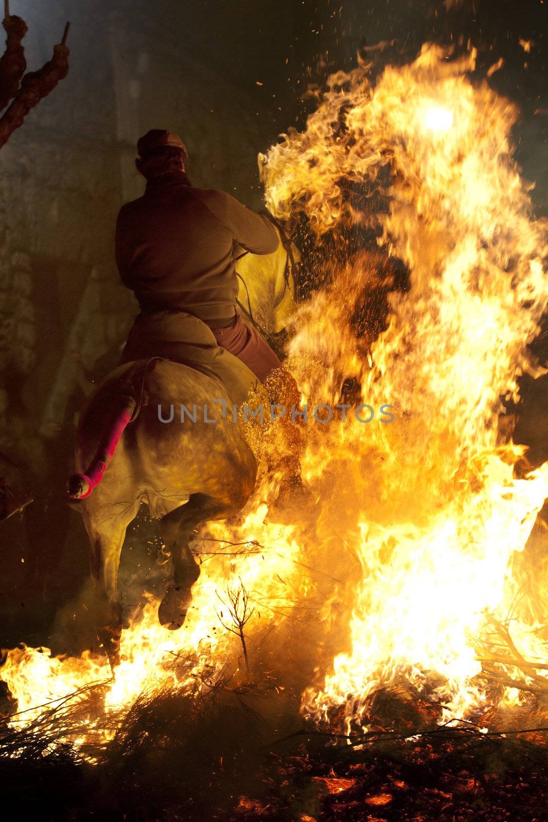 rider jumps the fire with his horse