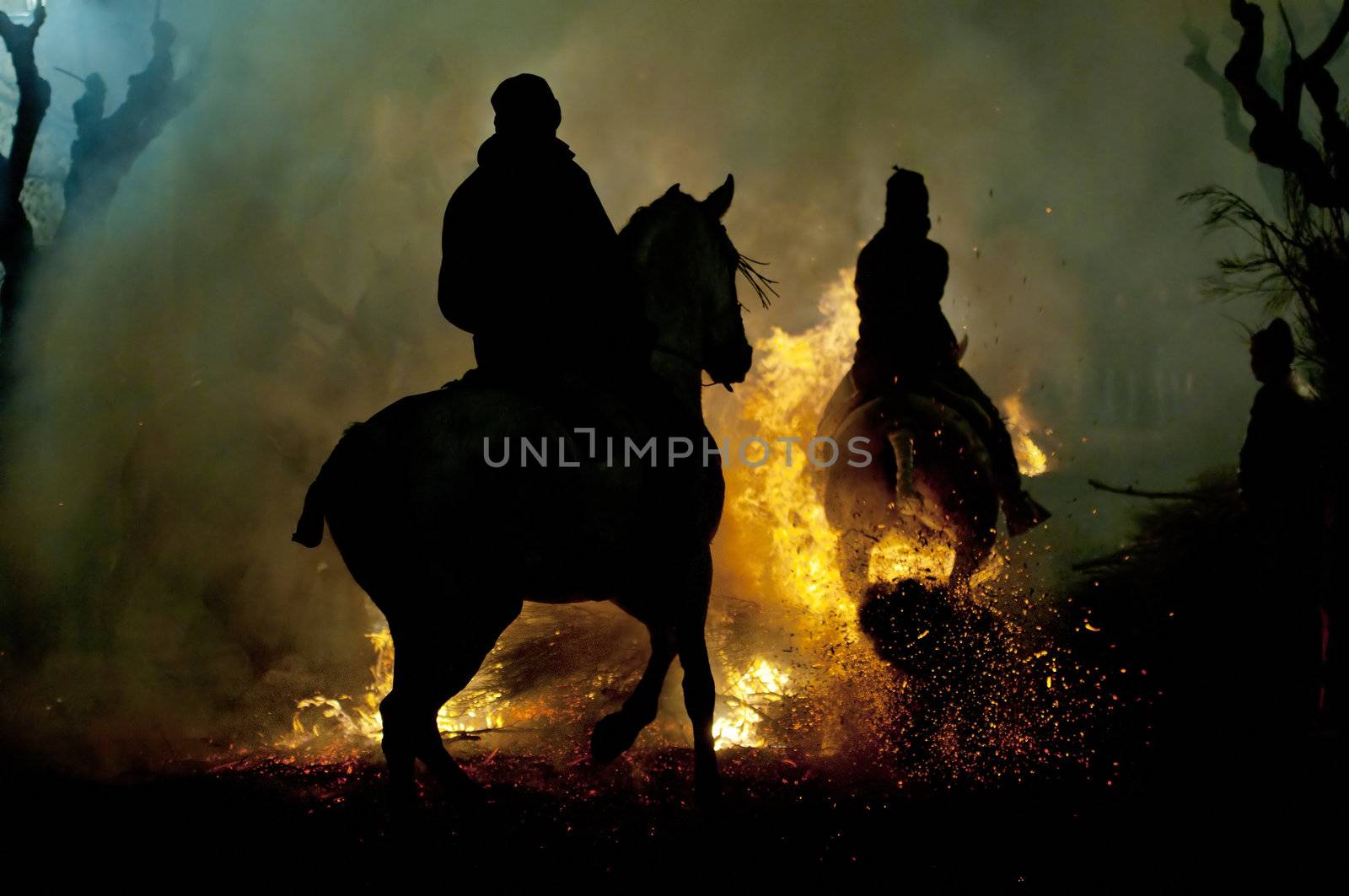 rider jumps the fire with his horse