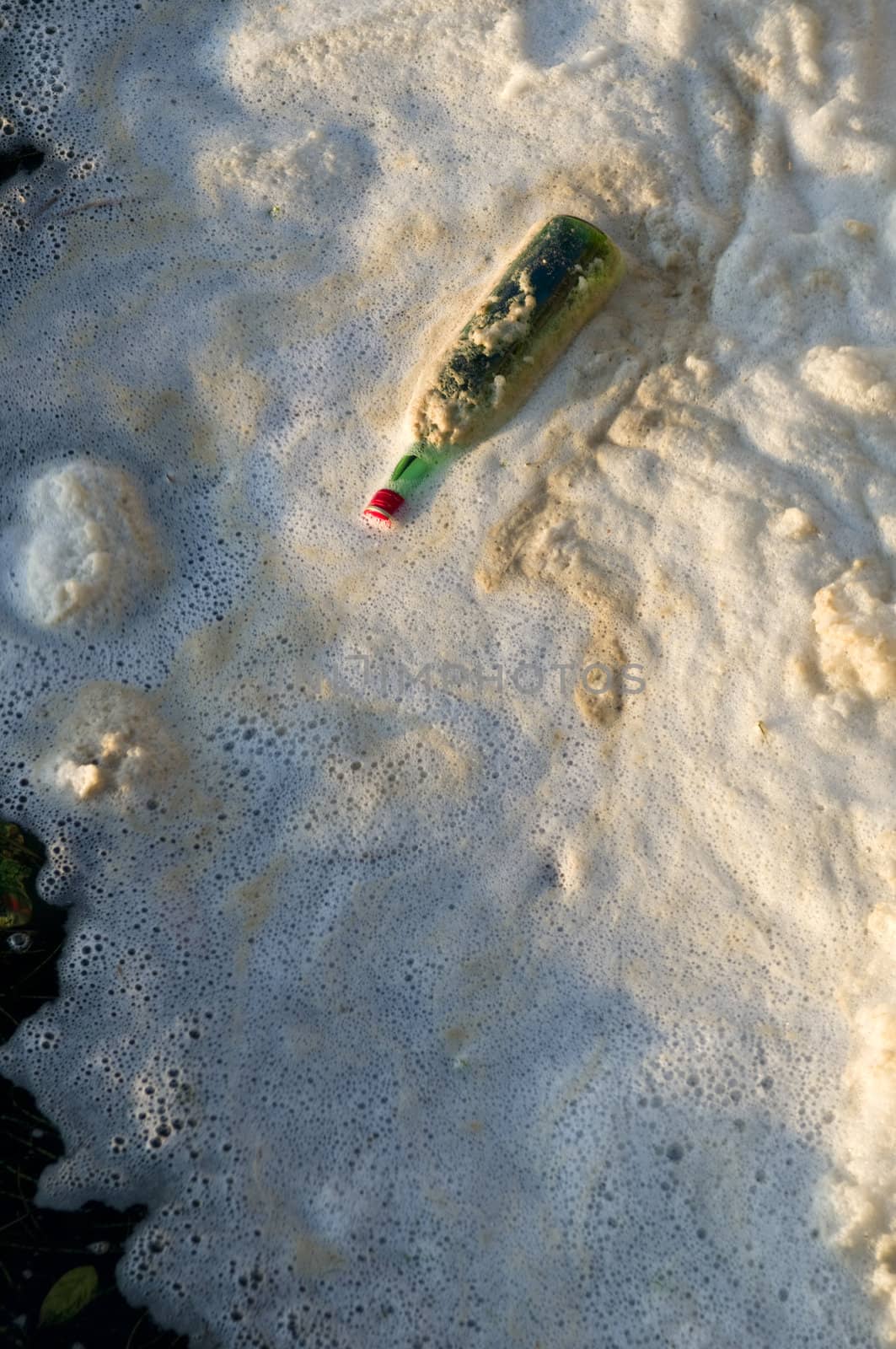 Water pollution, a bottle and foam on a river.