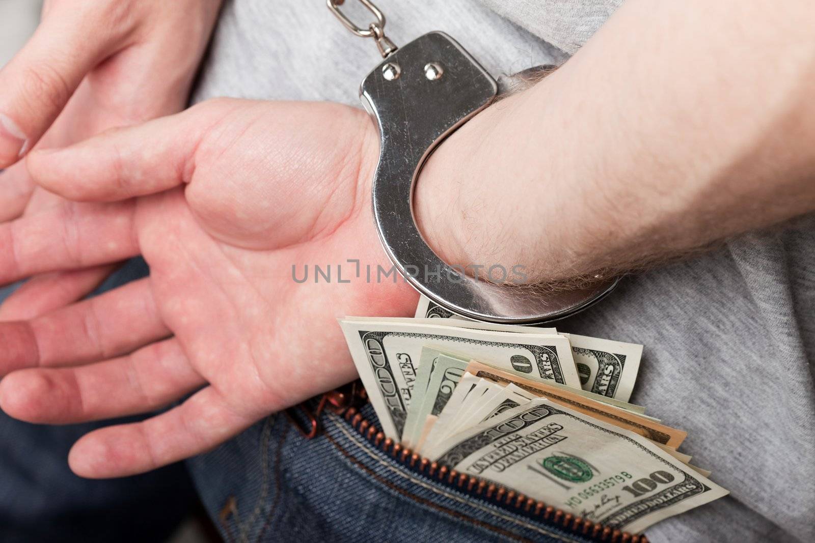 Handcuffs on hands hiding money by ia_64