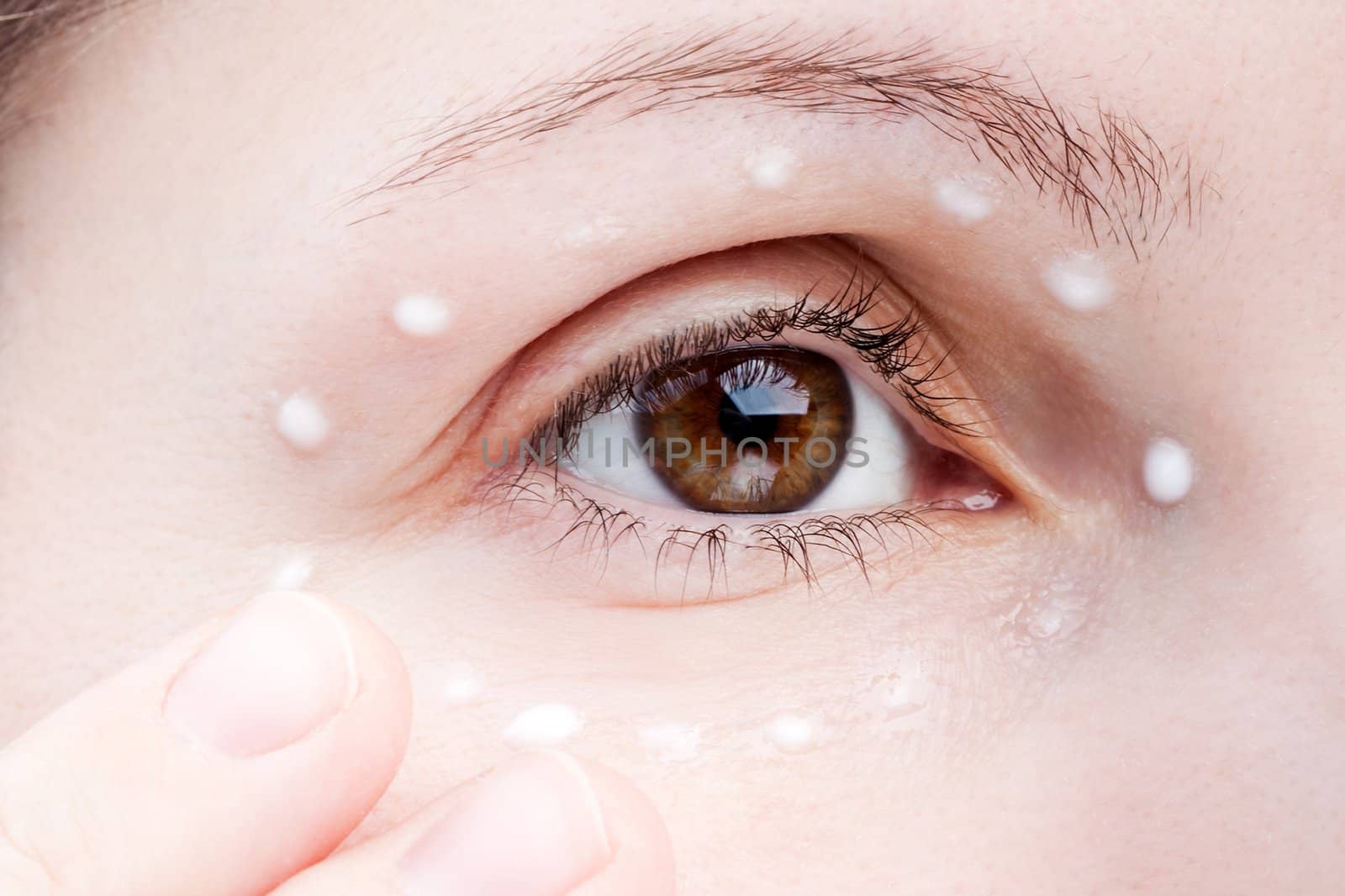 Women applying eye skin cream by ia_64