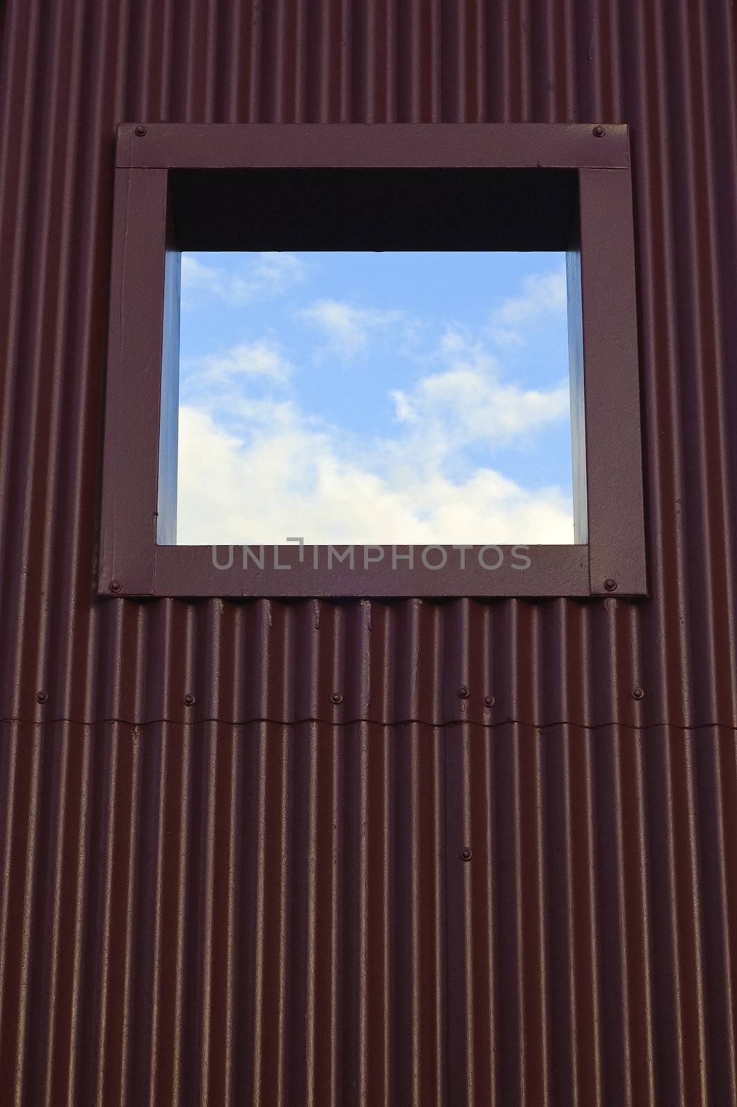 Window on metal structure showing a section of blue sky and clouds