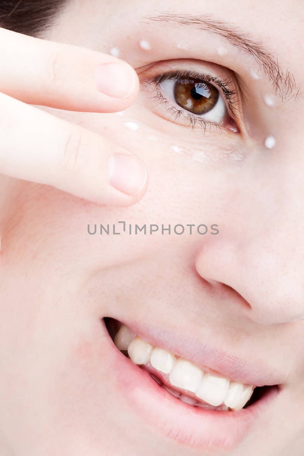 Women applying eye skin cream by ia_64