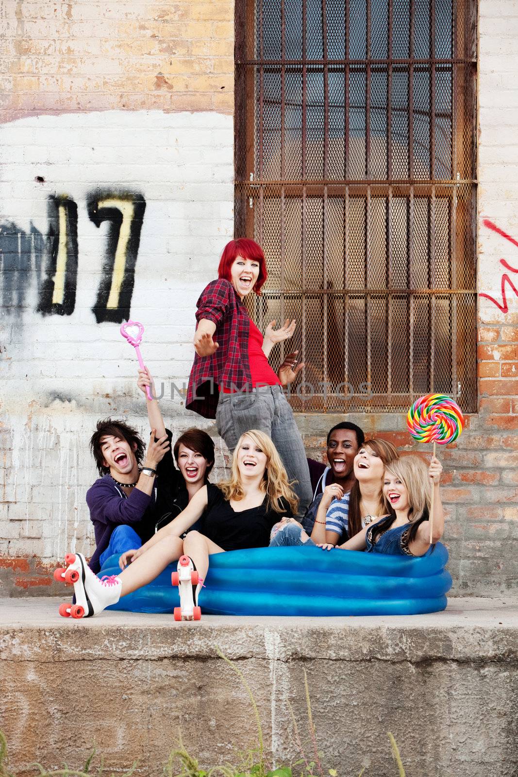 Crazy teen punks sit together in an inflatable pool behind an old warehouse downtown.