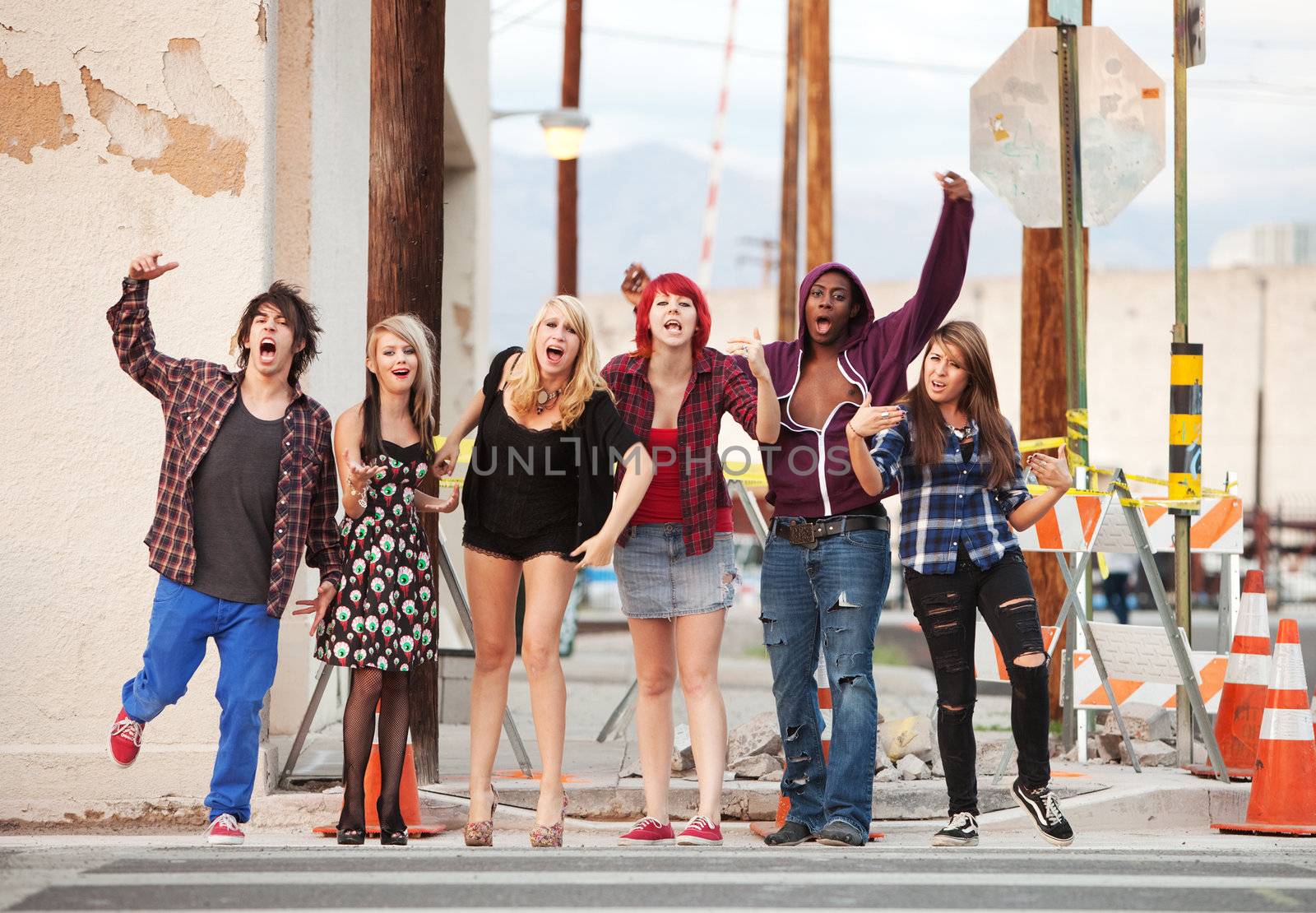 A group of angry punk rock teens shout loudly across the street towards the camera.