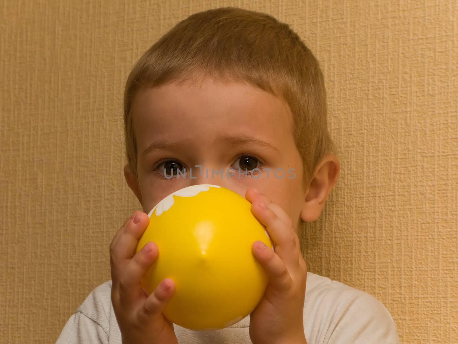 Little cheerful child inflating balloon for fun