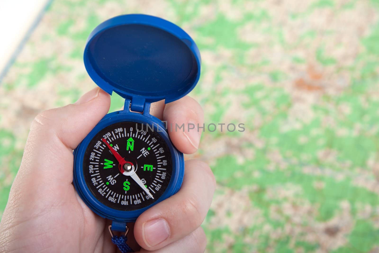 Hand holding travel north direction compass on map