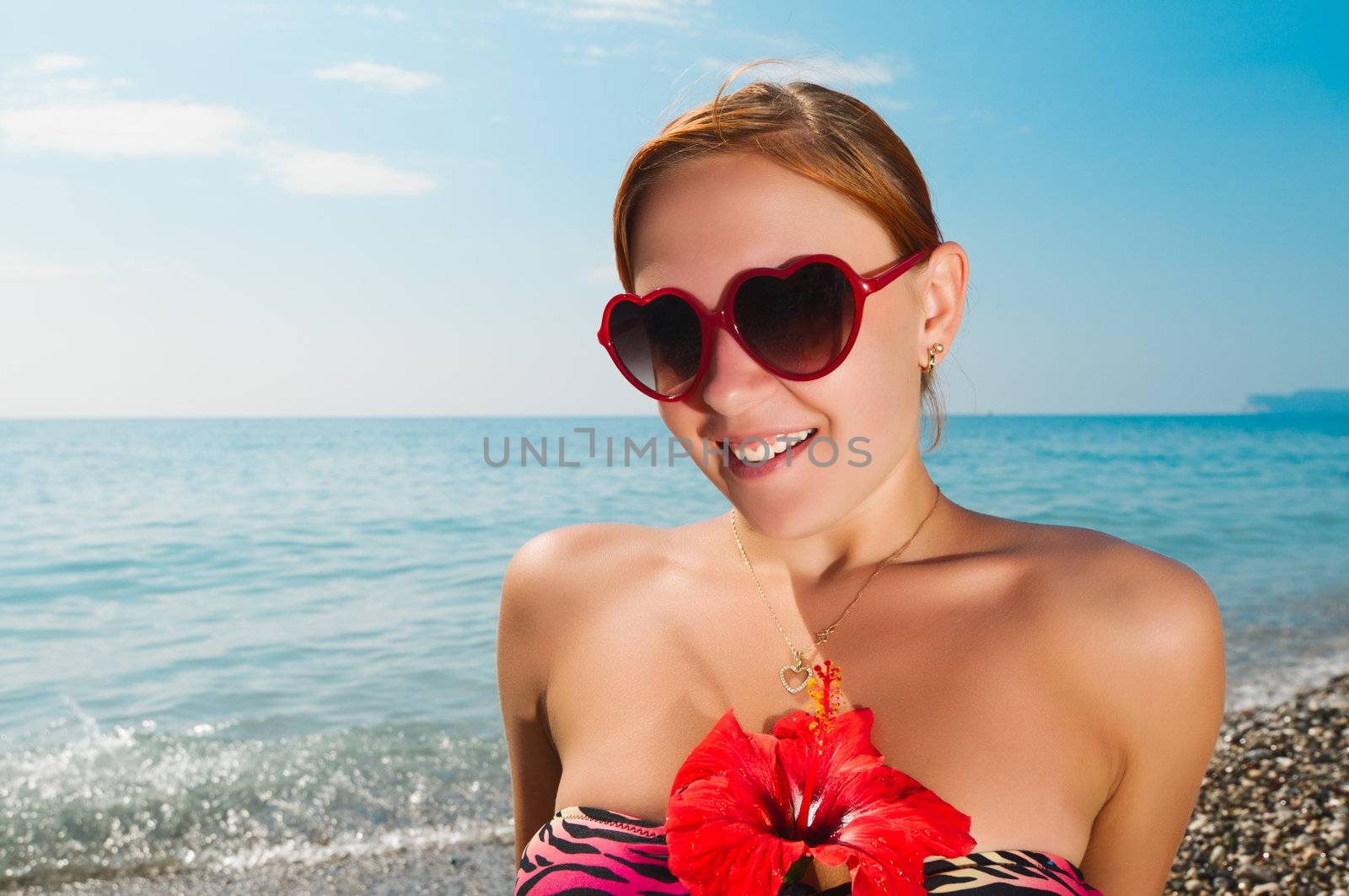 Sexy red girl wearing bikini and sunglasses at the beach