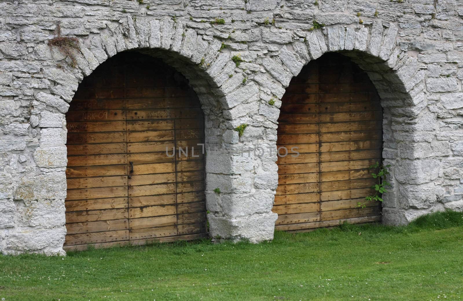 Two wooden doorways in solid stone wall.