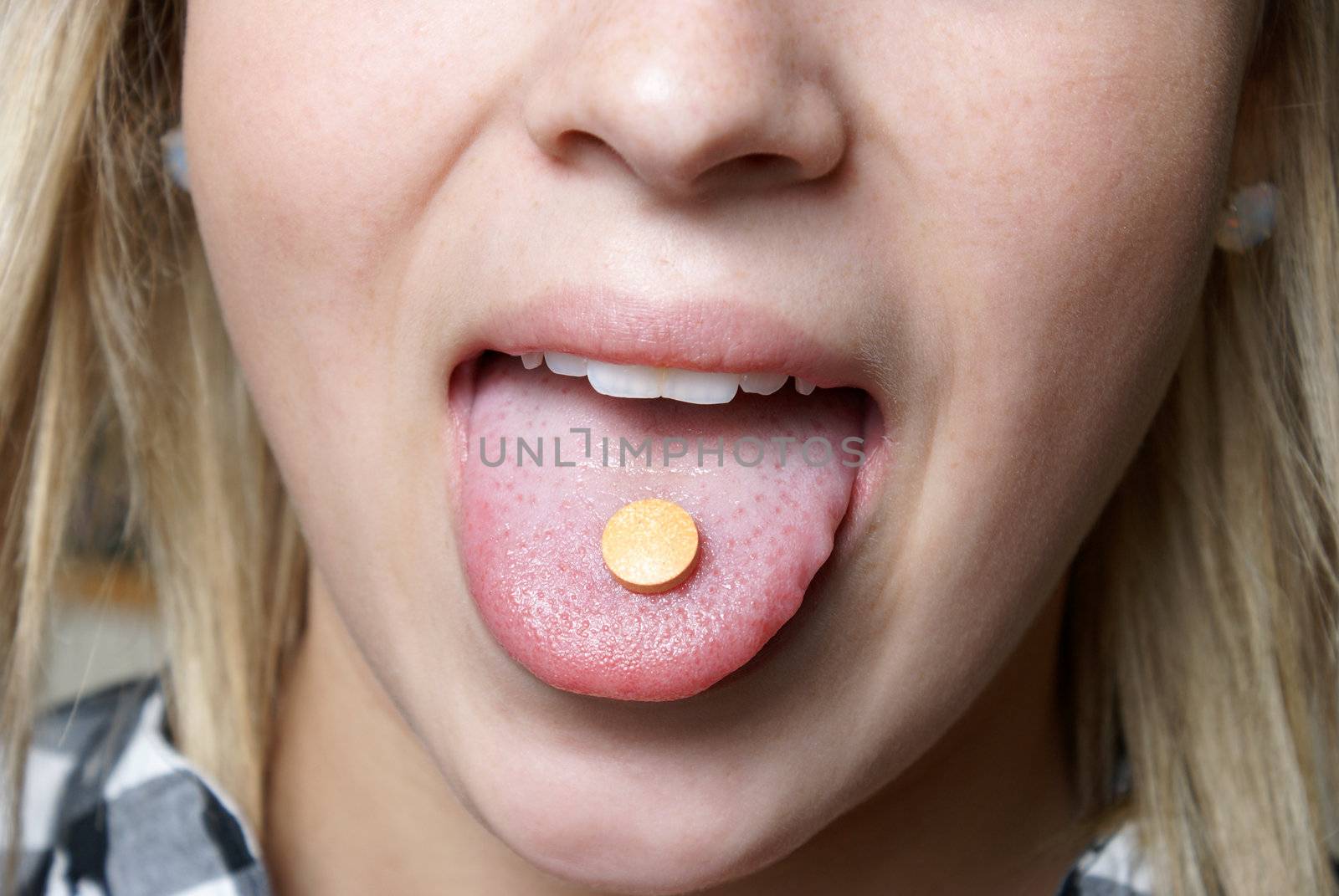 A young girl takes a vitamin c chewable tablet for supplementing her health.