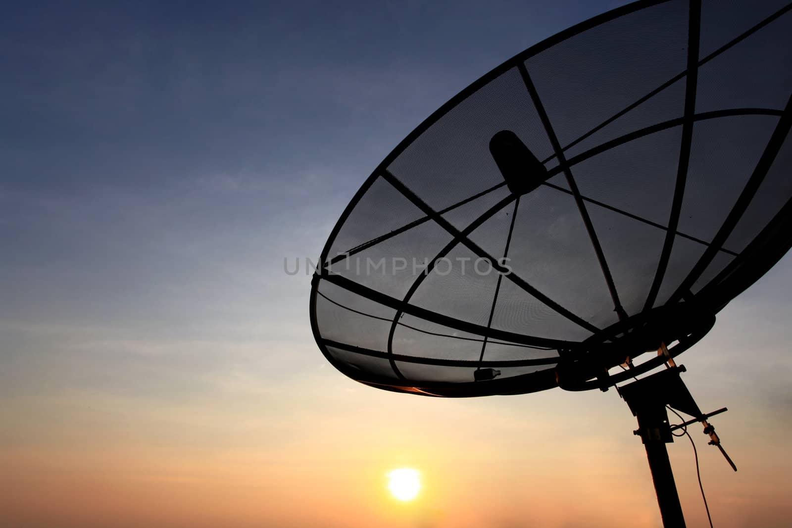 black antenna communication satellite dish over sunset sky in cityscape