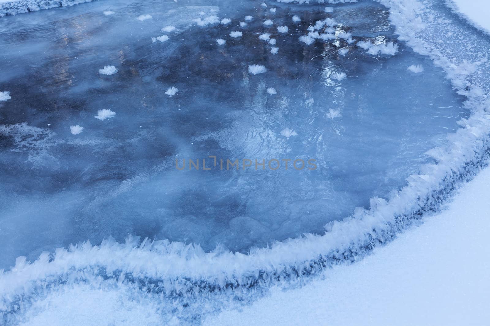 Image of frozen lake with ice edge covered with big icy snowflakes