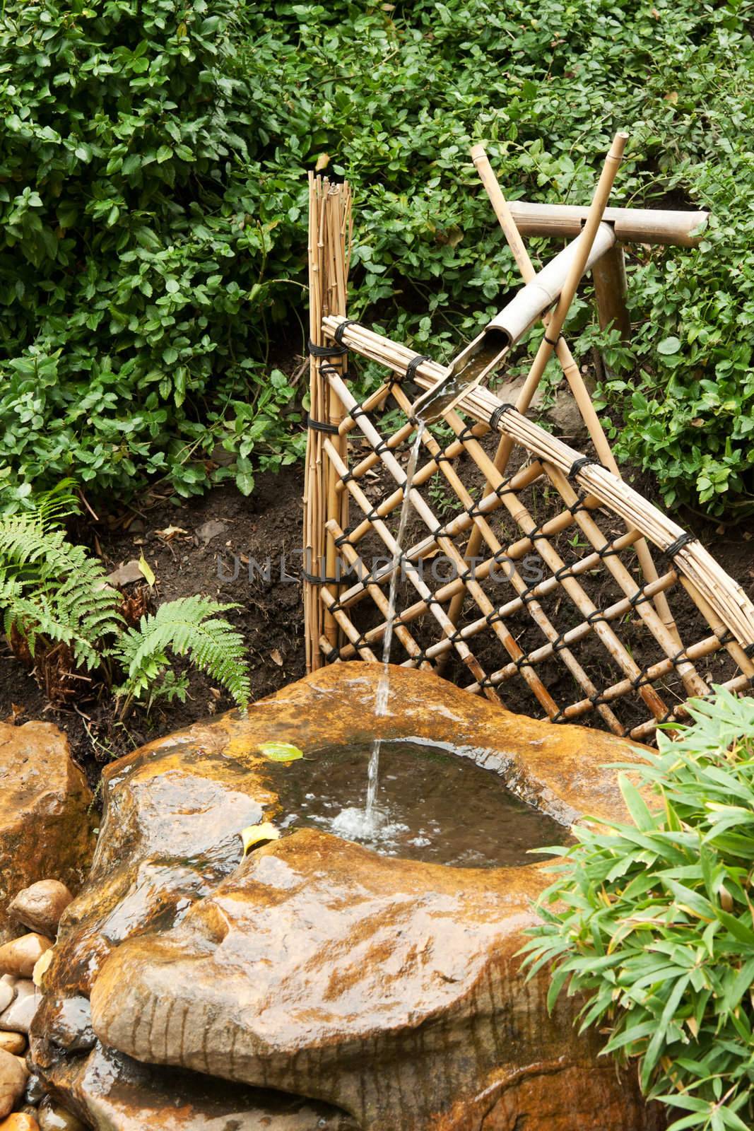 Bamboo fence and pipe, flows water in wood