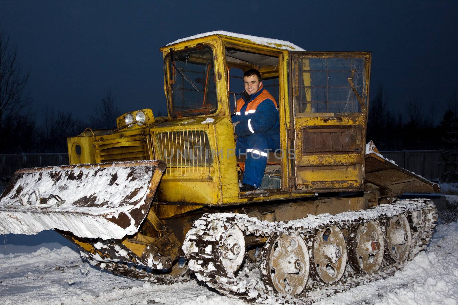 
Tractor clearing snow at night. Tracked vehicles. 
