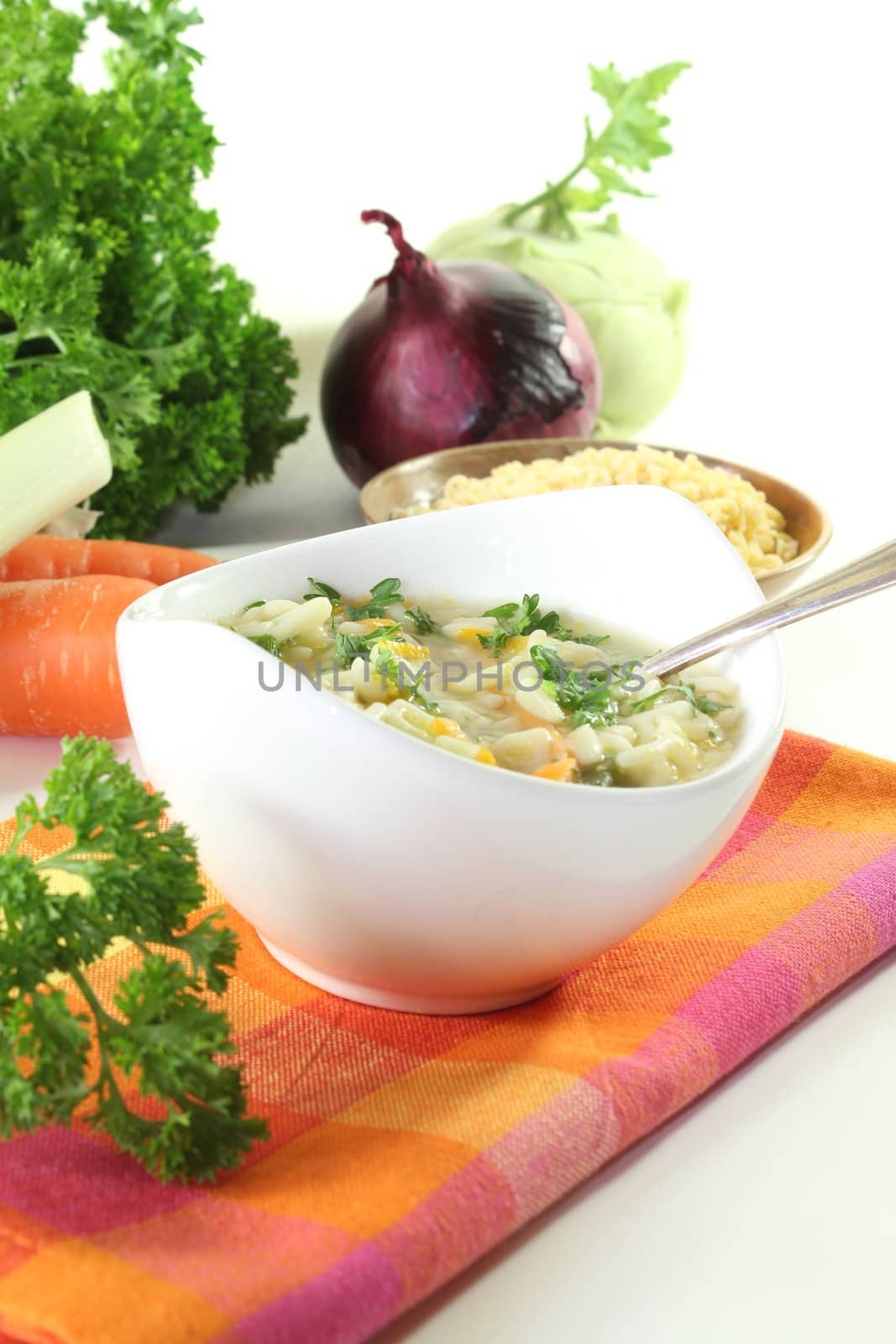 Alphabet soup with carrots, leeks, onions, parsley and spoon