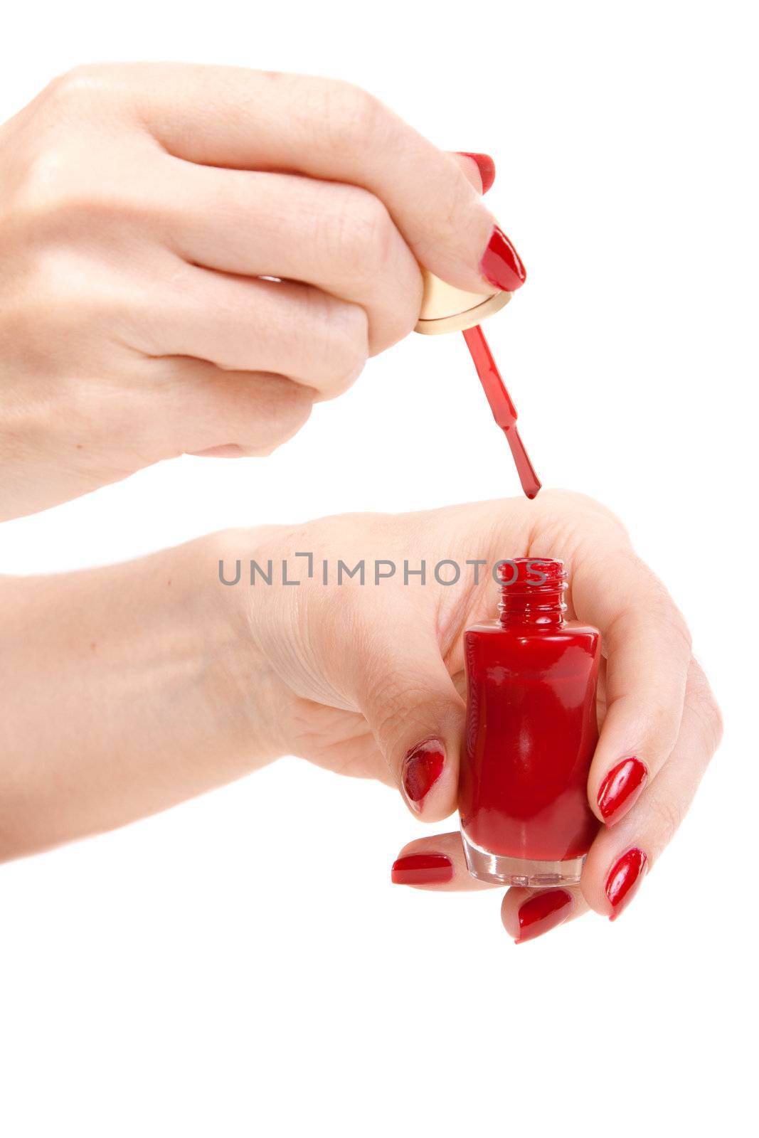 Women's hands with a bottle of red nail polish