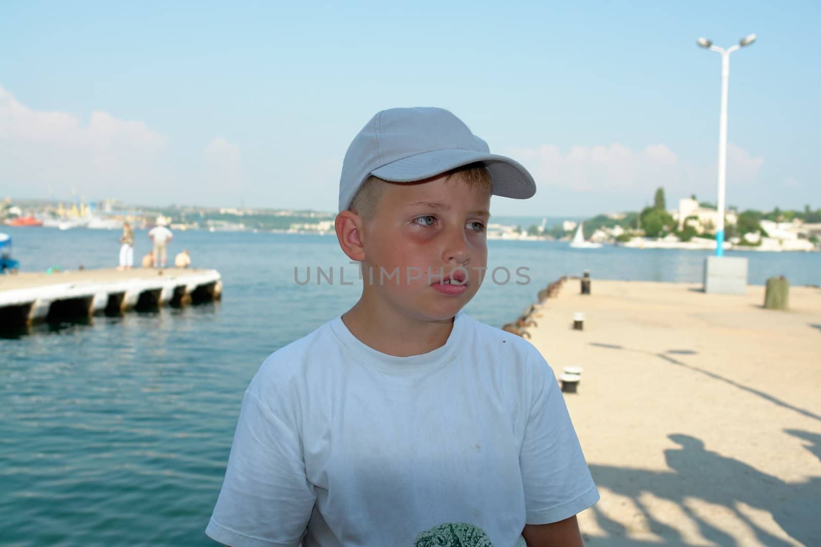 sad little boy in front of water