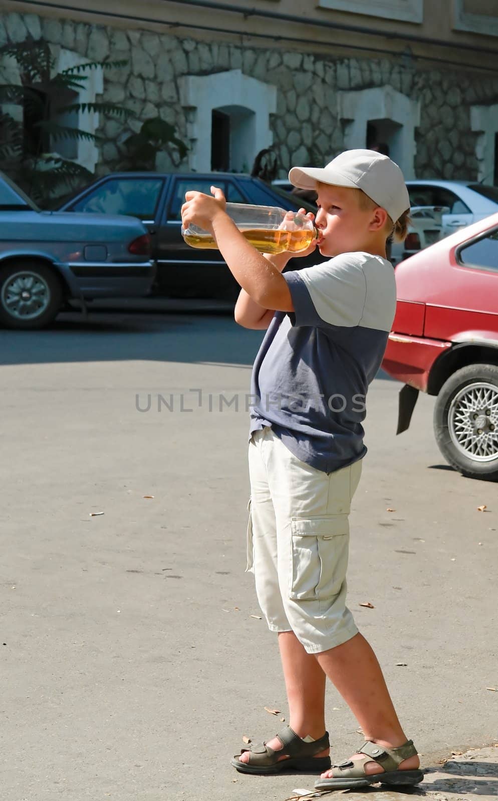 The little boy drinks water from the big bottle