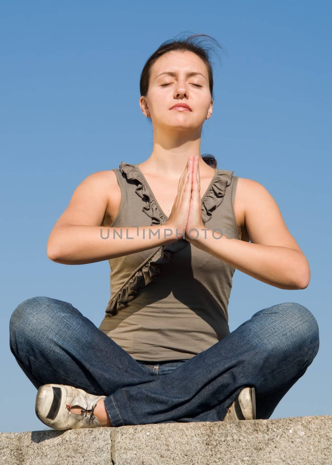 Meditation. The girl meditates with sky at background.