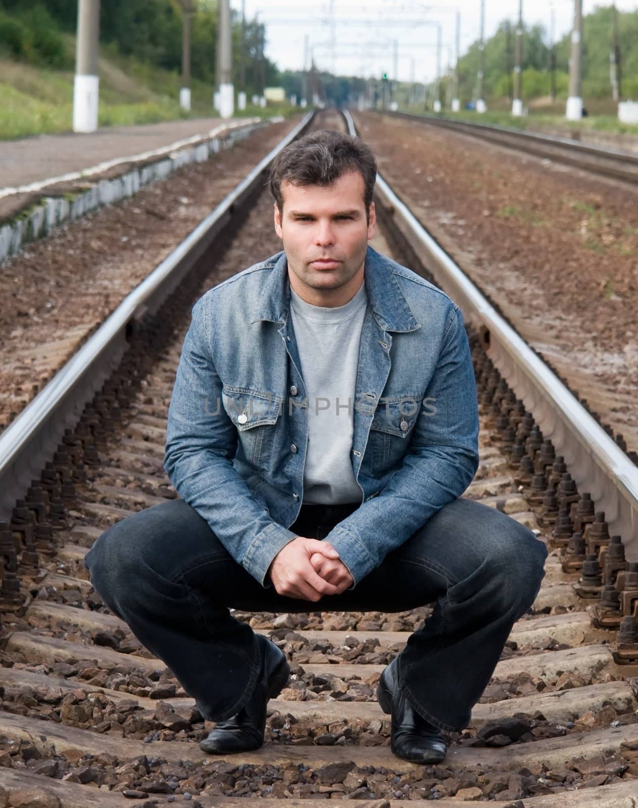 The young man sits on the railway