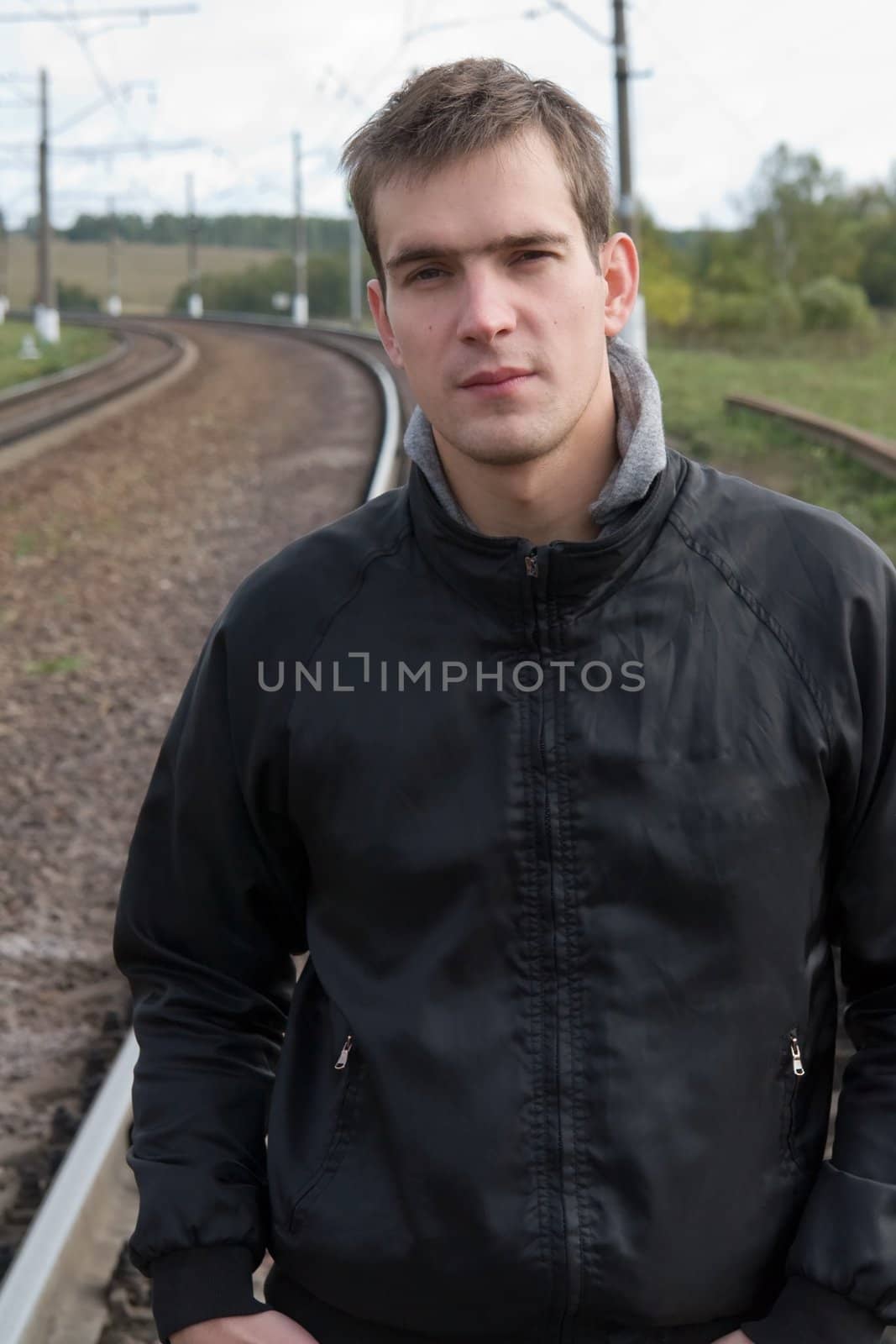 Cloudy day. The young man against the railway