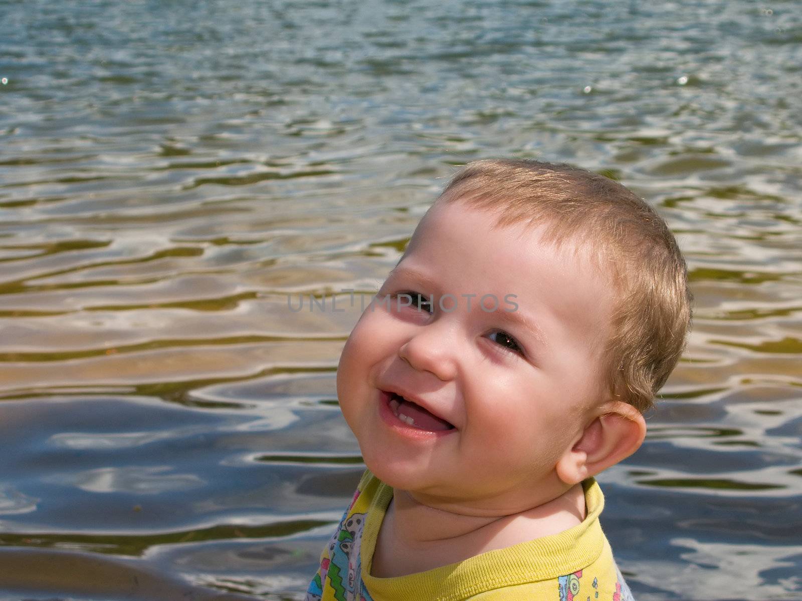 Little child smiling on water beach at summer