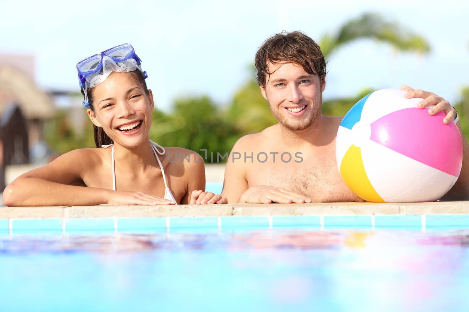 Summer vacation couple having fun in pool on sunny day in tropical resort