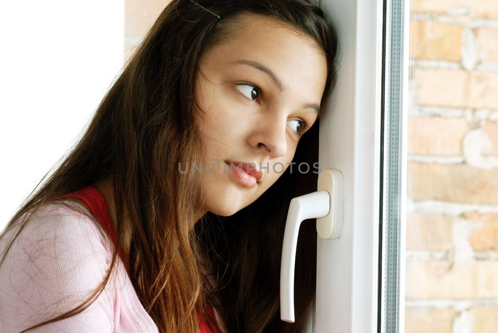 Teenage girl looking out  window by simply
