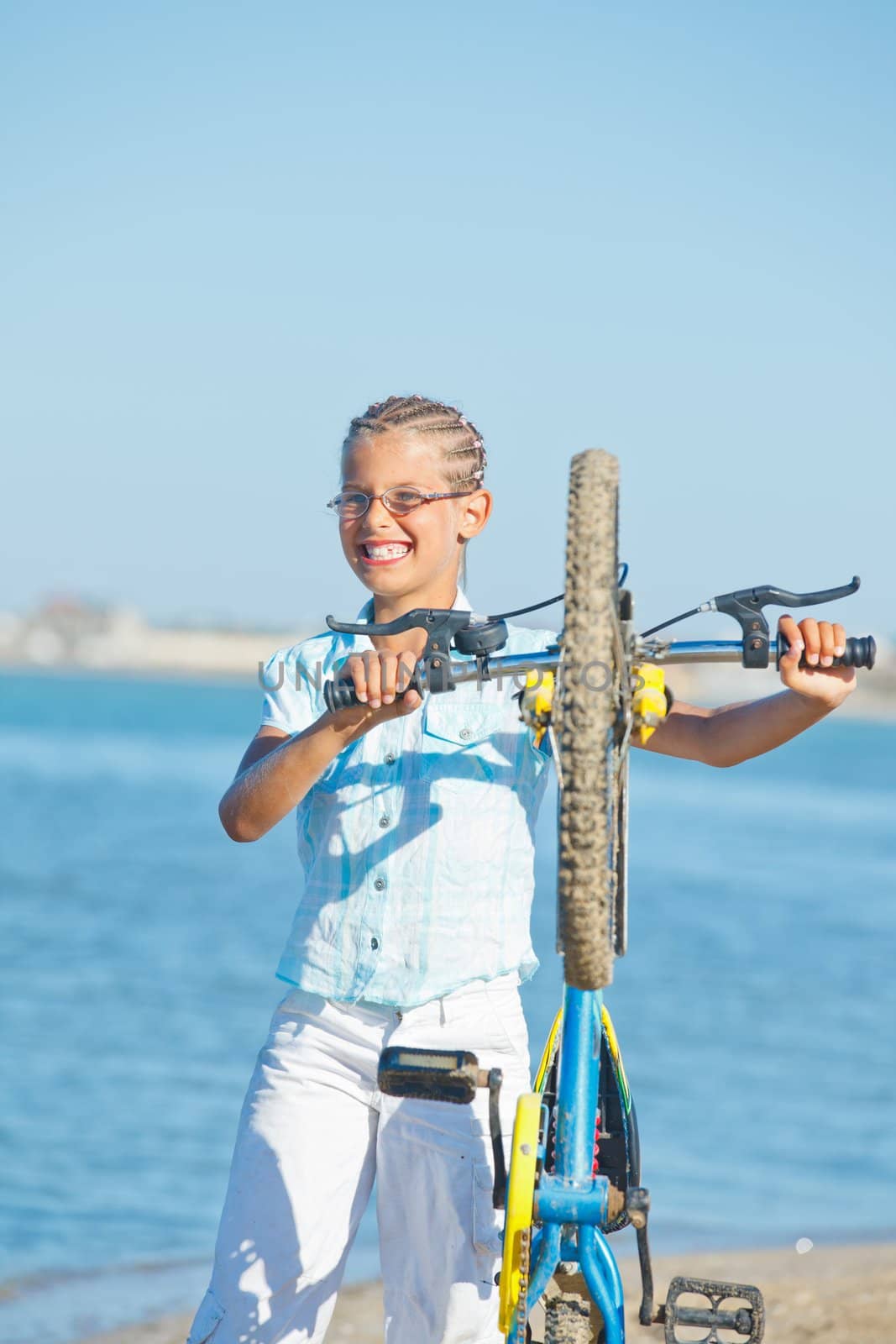 beautiful young girl standing with her bicycle. the background sea