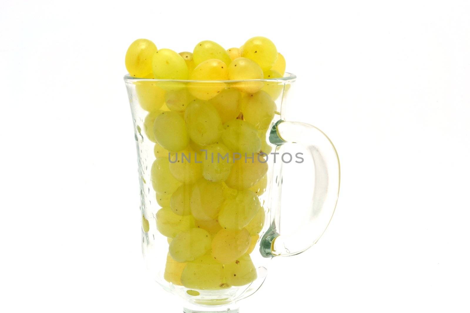 The glass cup full of yellow grapes