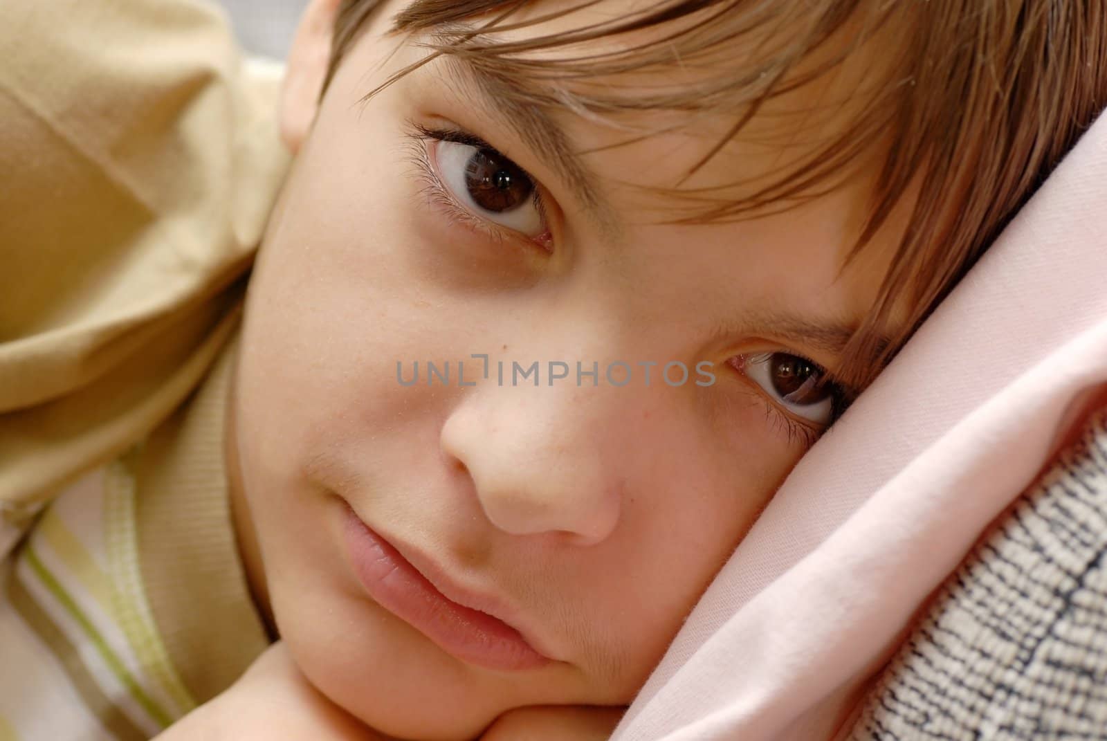 caucasian boy portrait, lying on pillow with arm under cheek