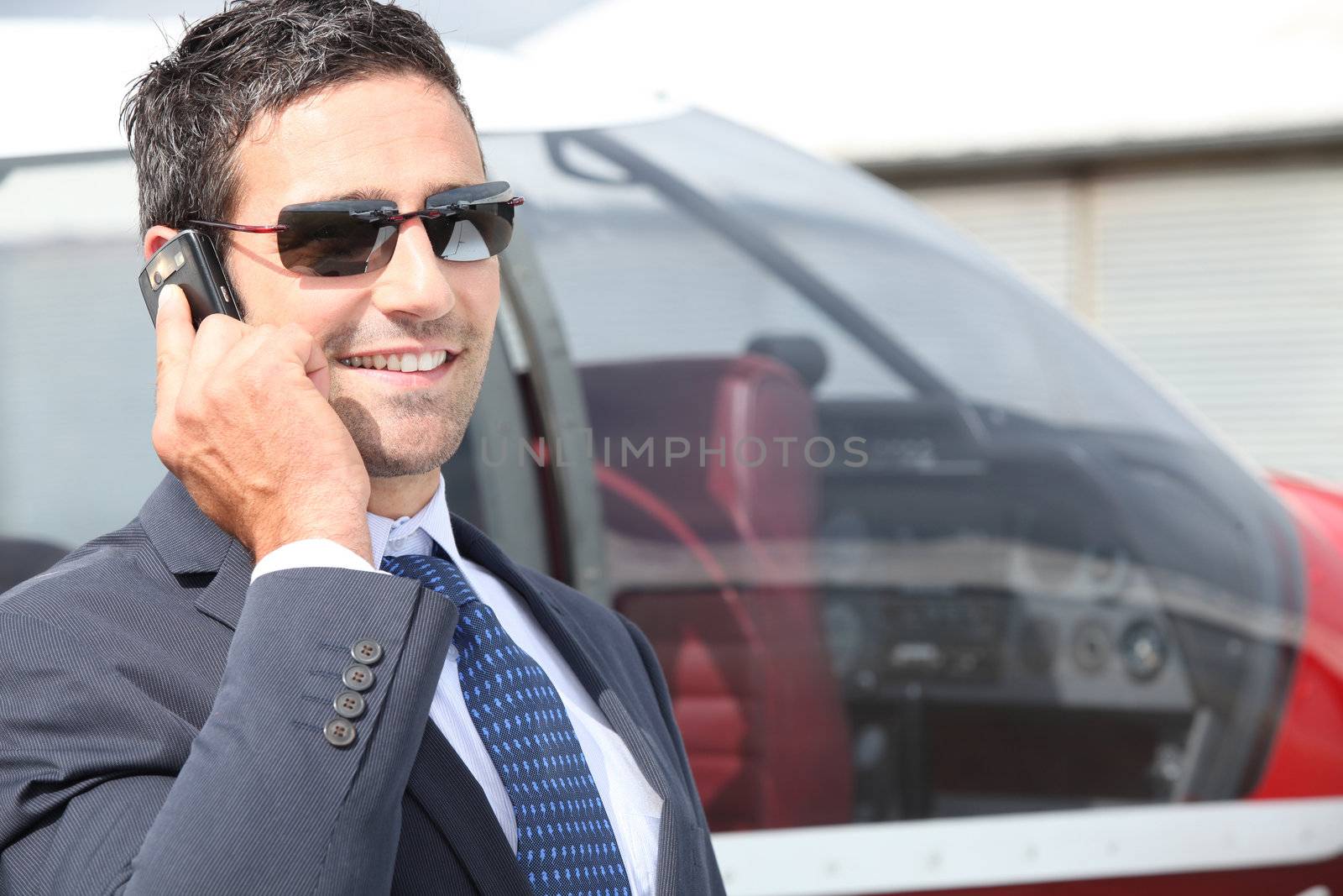 Businessman using a cellphone next to his private plane