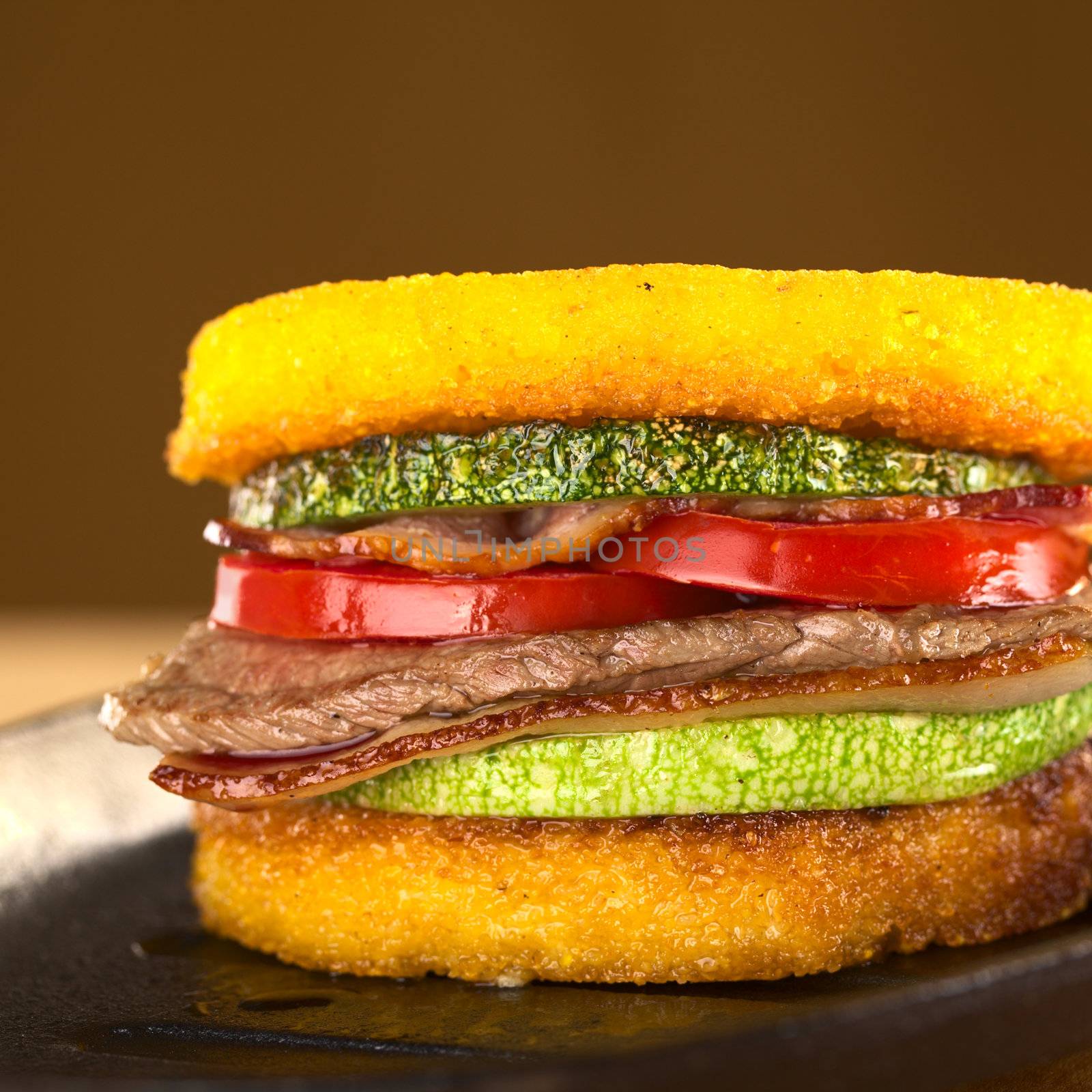 Polenta burger with fried zucchini, bacon, beef and tomato (Selective Focus, Focus on the front of the burger)