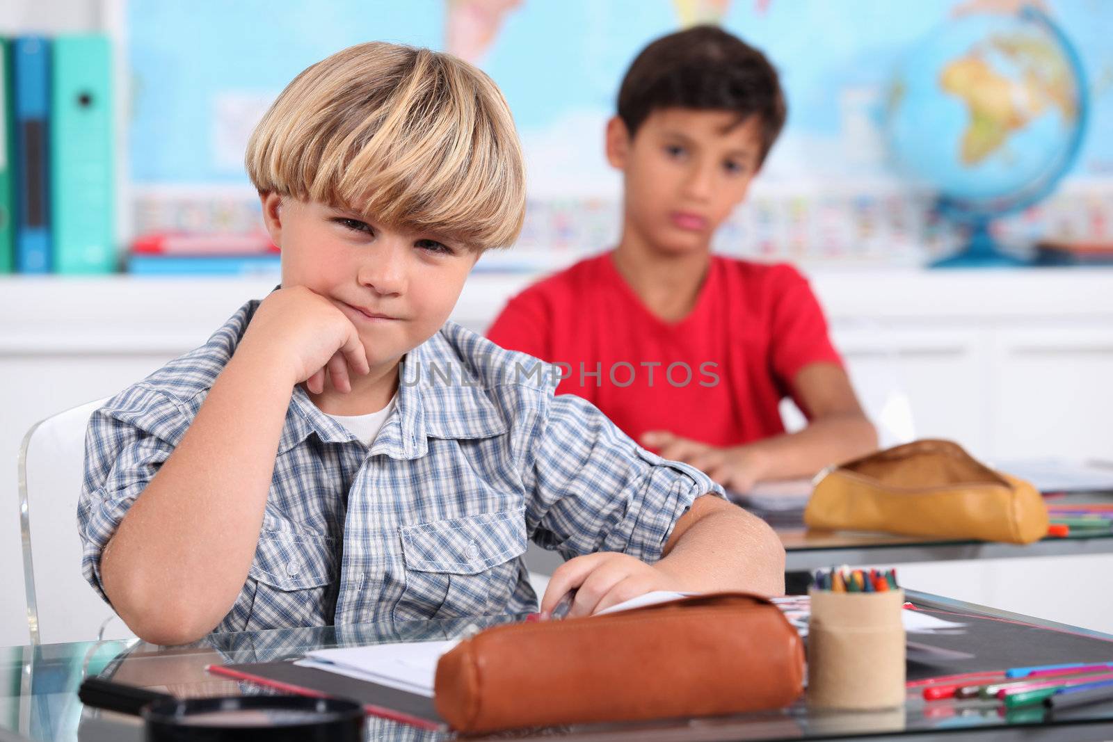 schoolboys seated at desk in classroom by phovoir