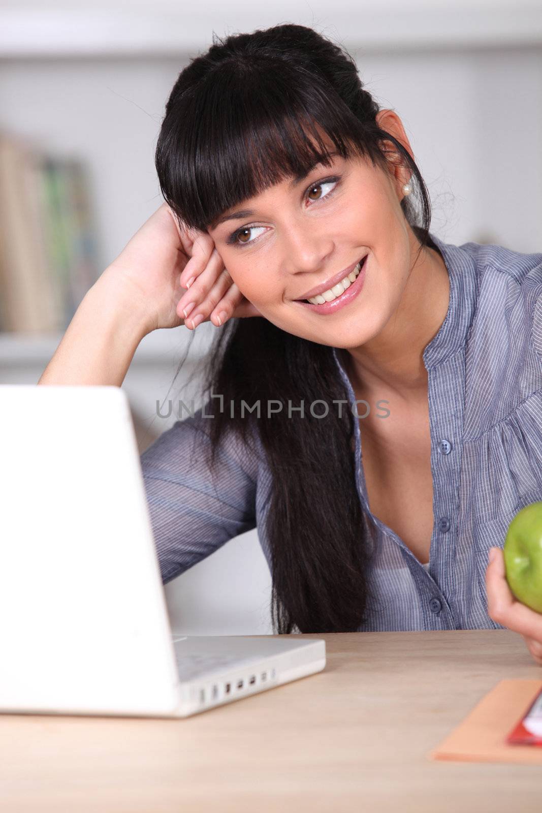 Woman working on her laptop and holding an apple by phovoir