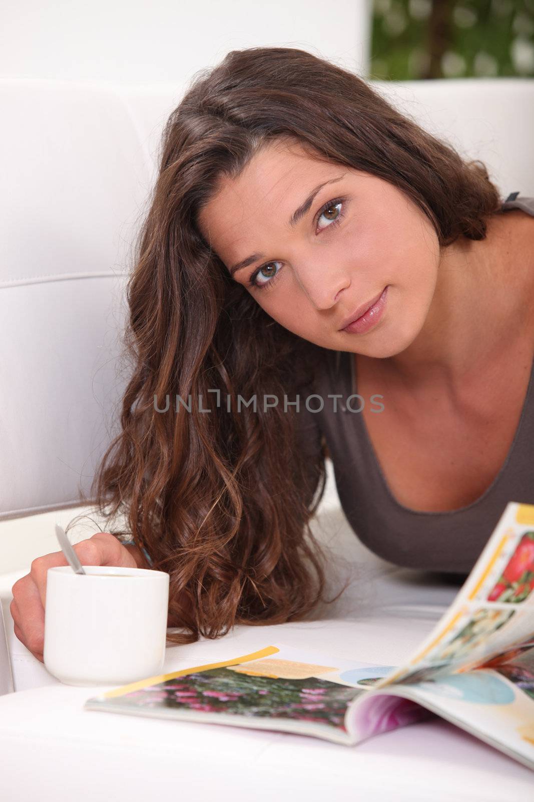 Woman reading a book while drinking a cup of tea by phovoir