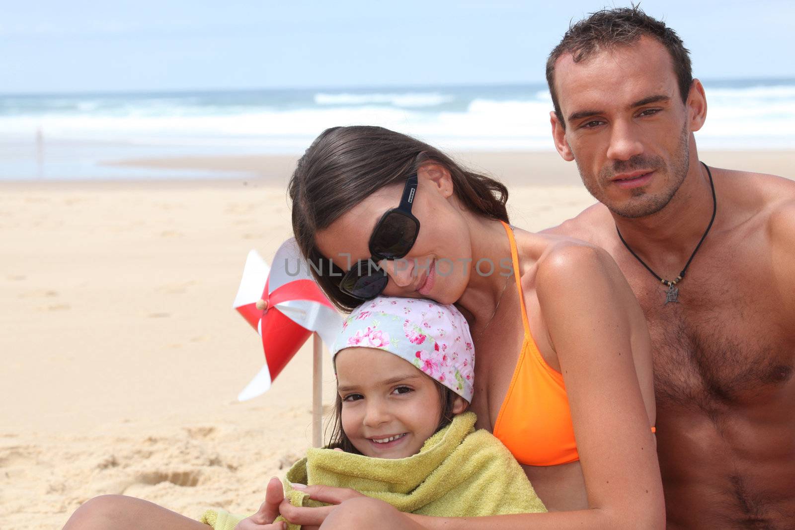 couple with their little girl on the beach by phovoir